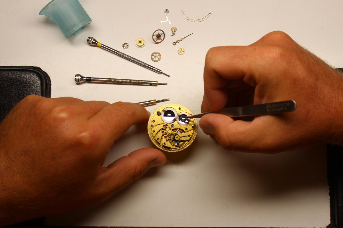 Mani al lavoro su un movimento di orologio nel laboratorio Dalmasso